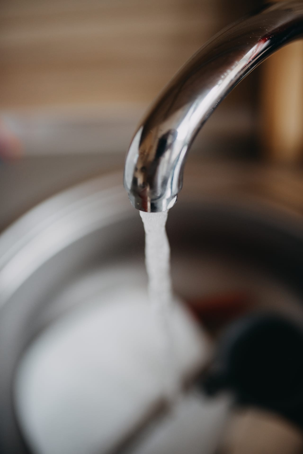 Water flowing from a chrome kitchen faucet into a sink